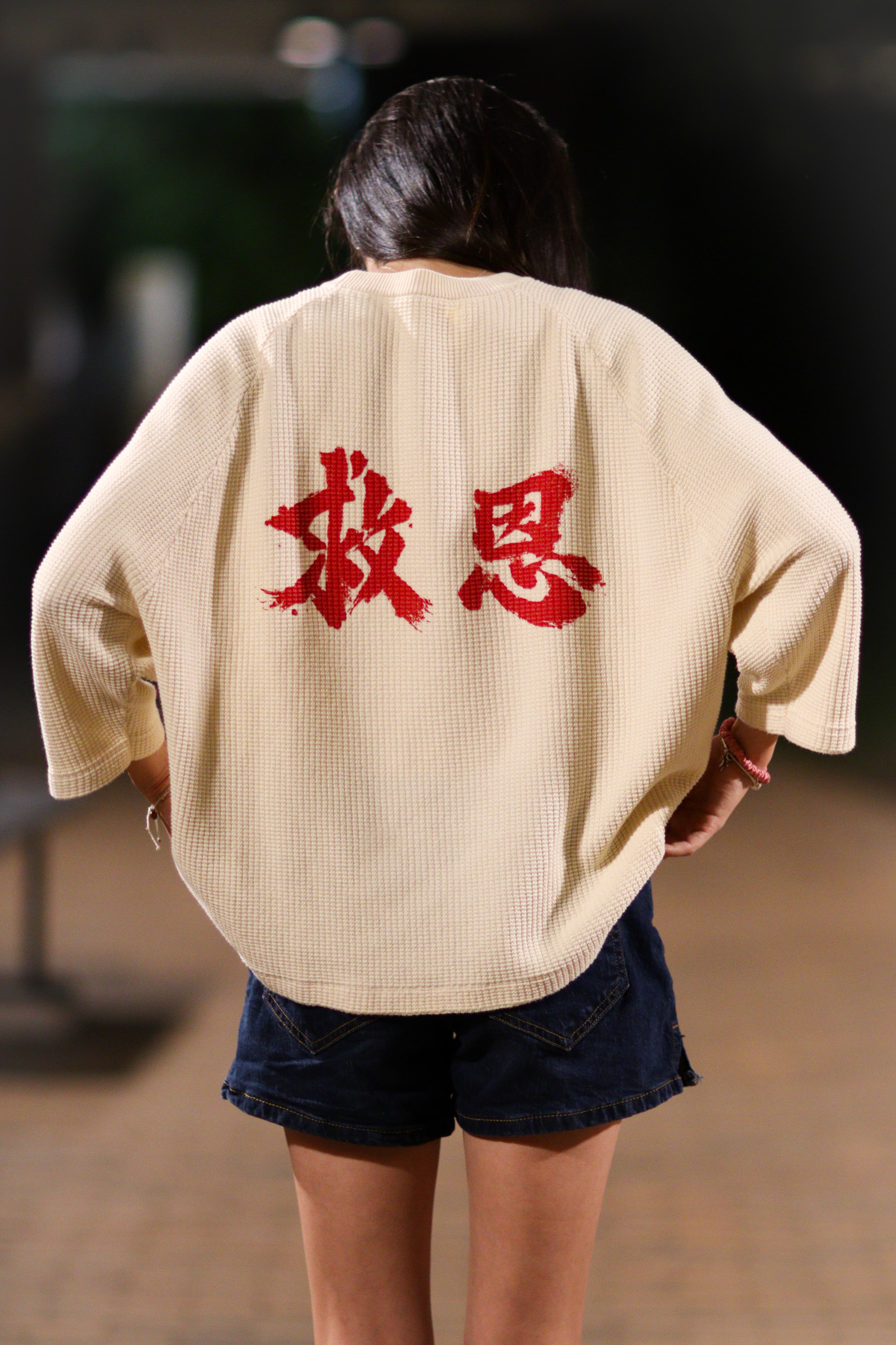On-model, back, walking away, the 救恩 mark visible on the waffle knit.