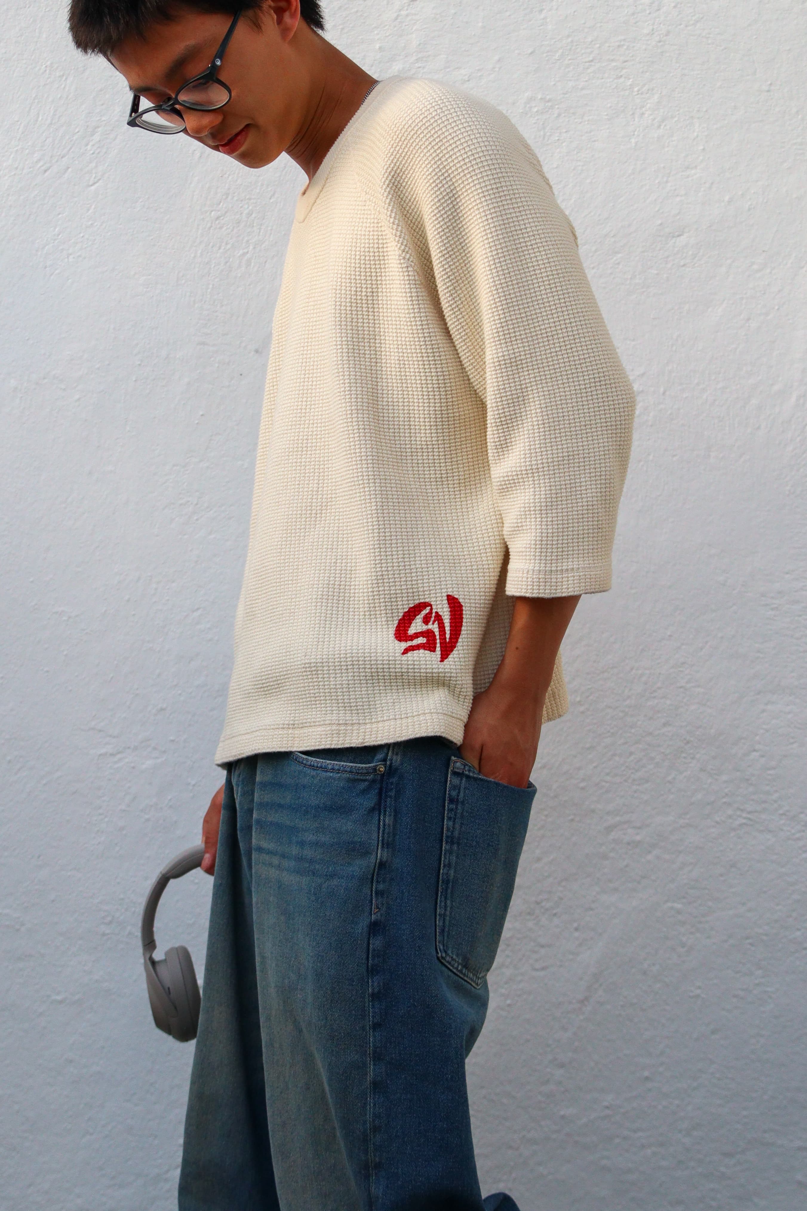 On-model, male, side profile, plain studio background, showing the sleeve length and hem mark.